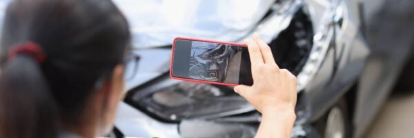 A woman takes photos of a car accident after a Pittsburgh crash