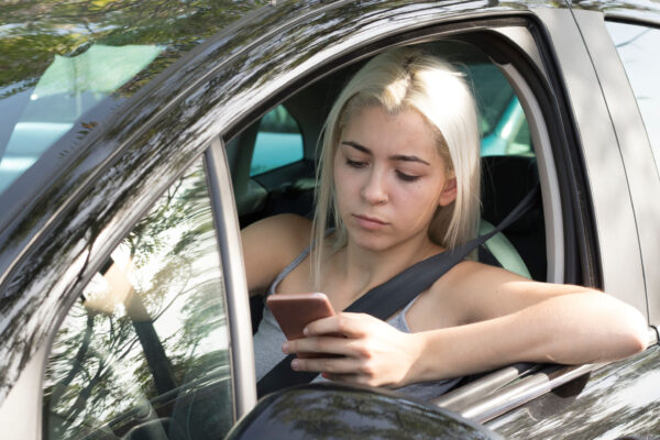 A young female teen driver looking at her phone while driving.