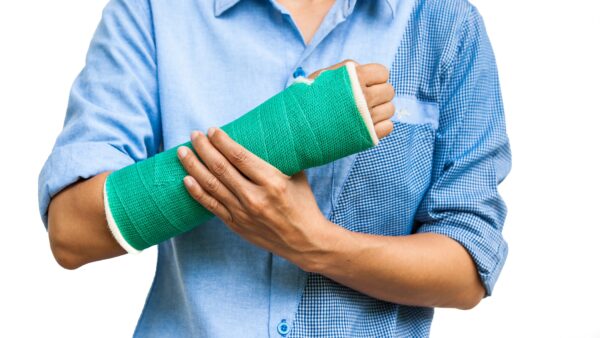 Man in blue shirt with a broken wrist in a teal cast.