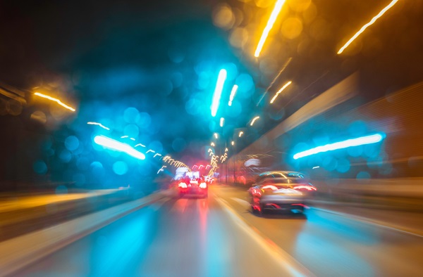 Blurred nighttime road scene with colorful lights and cars, symbolizing impaired driving or distracted driving during December.