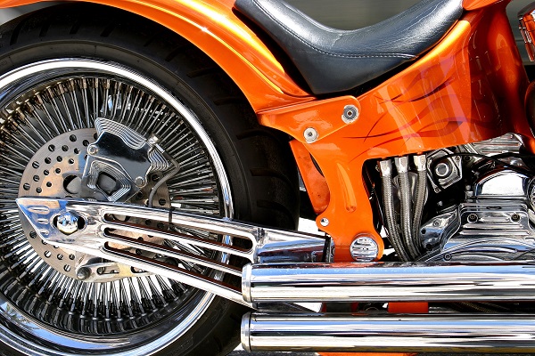 Low seat, fat tires, orange paintwork and tons of chrome on a custom chopper motorcycle.