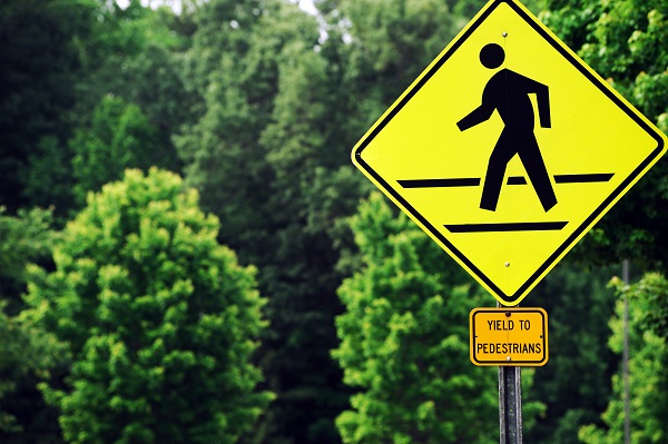 A bright yellow pedestrian crossing sign.